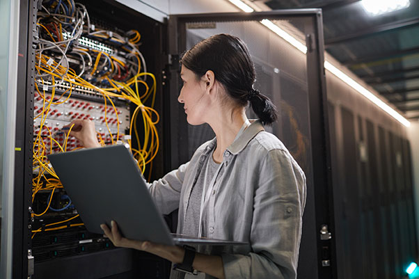 Technicienne informatique brune réalisant la maintenance d’un serveur informatique, en utilisant son ordinateur