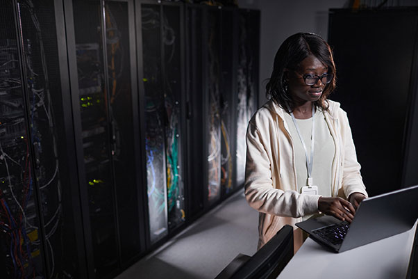 Jeune technicienne informatique afro-américaine travaillant sur son ordinateur, dans un data center